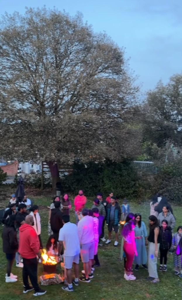 Large outdoor social event with bonfire and colourful lighting at The Queens Road Hotel