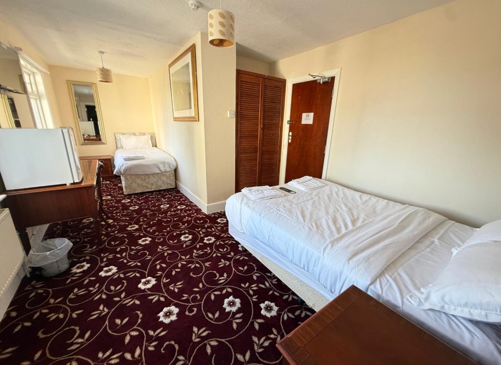 Standard twin room with two single beds, white linens, and patterned carpet at The Queens Road Hotel